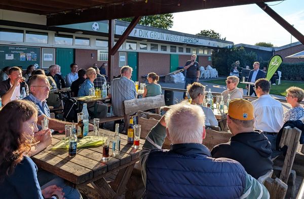 Gruppe von Menschen auf Terrasse hört 2 Rednern zu
