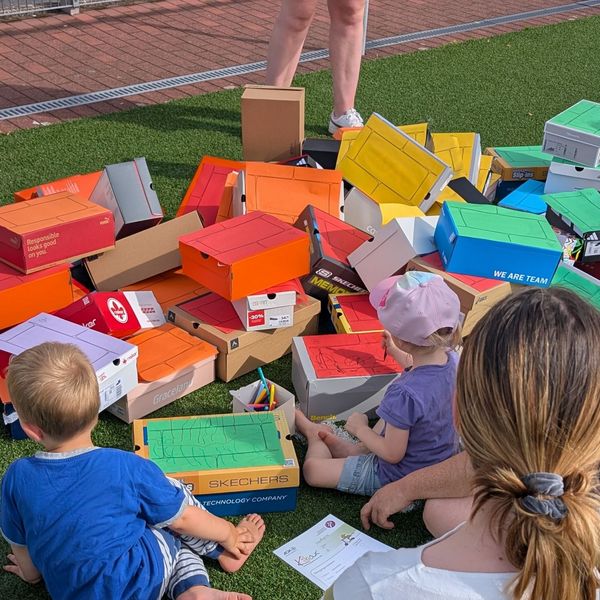 Kinder mit Bausteinen aus Pappkartons in Regenbogenfarben