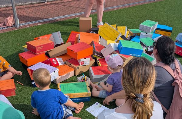 Kinder mit Bausteinen aus Pappkartons in Regenbogenfarben